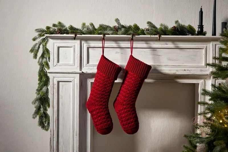 Two red heirloom knit Christmas stockings hanging on a mantel