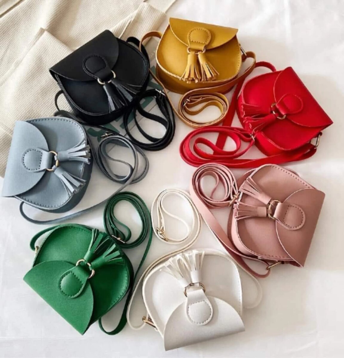 Eight colorful My First Purse vegan leather crossbody purses with tassels, arranged in a circle