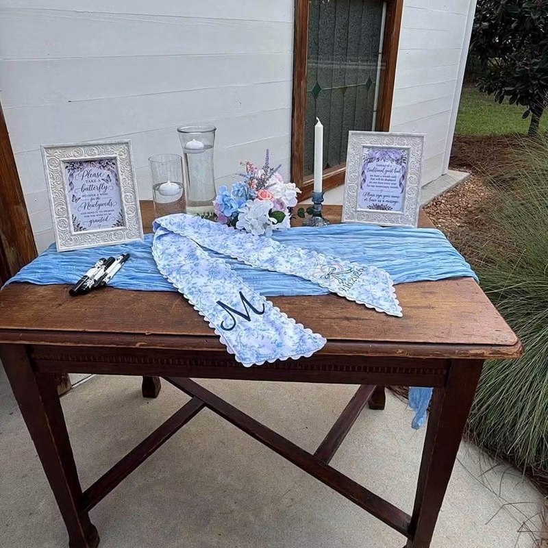 Embroidered wedding wreath sash laid out on a guest book table