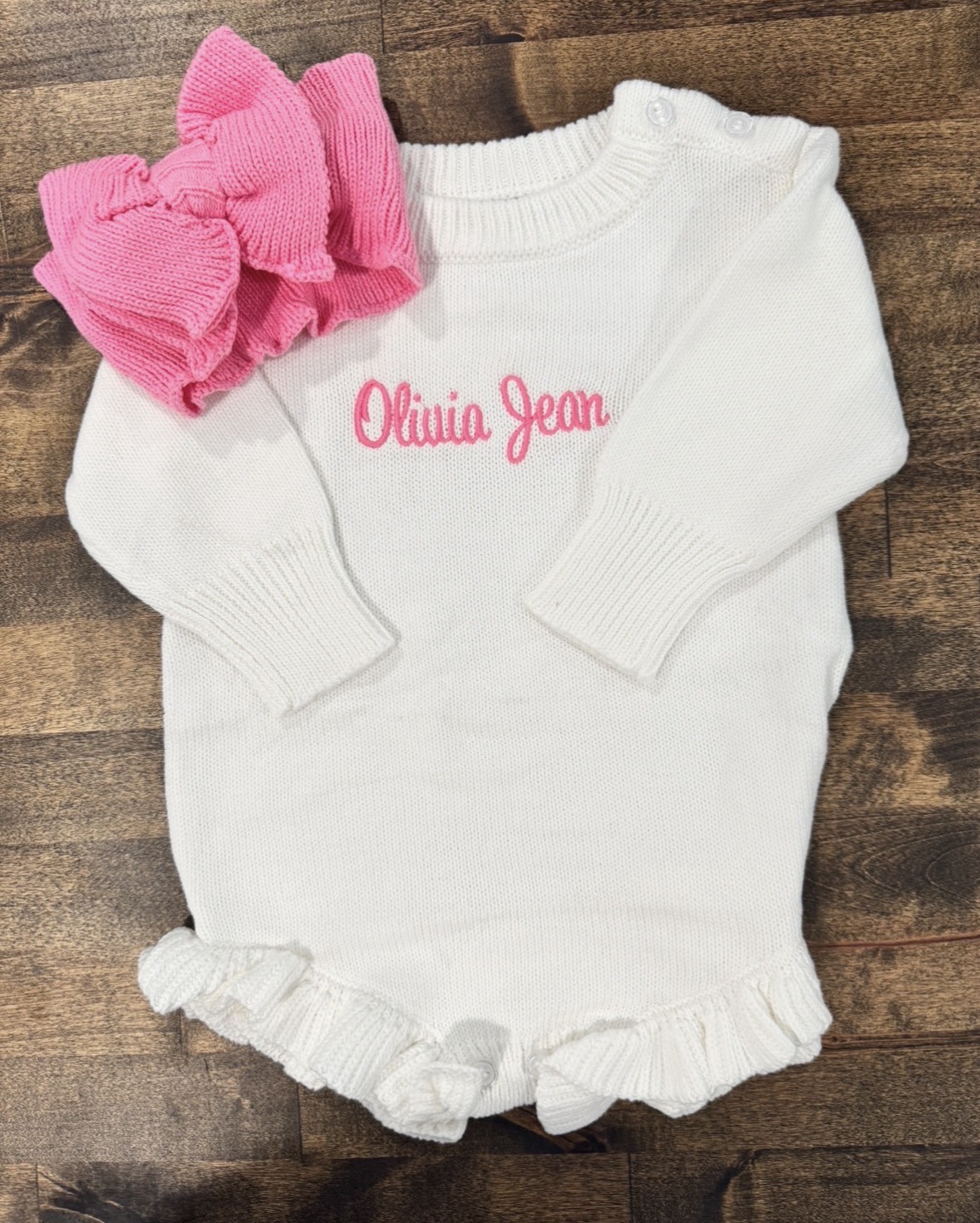 White ruffle knit romper monogrammed Olivia Jean, shown with a matching pink oversized knit bow