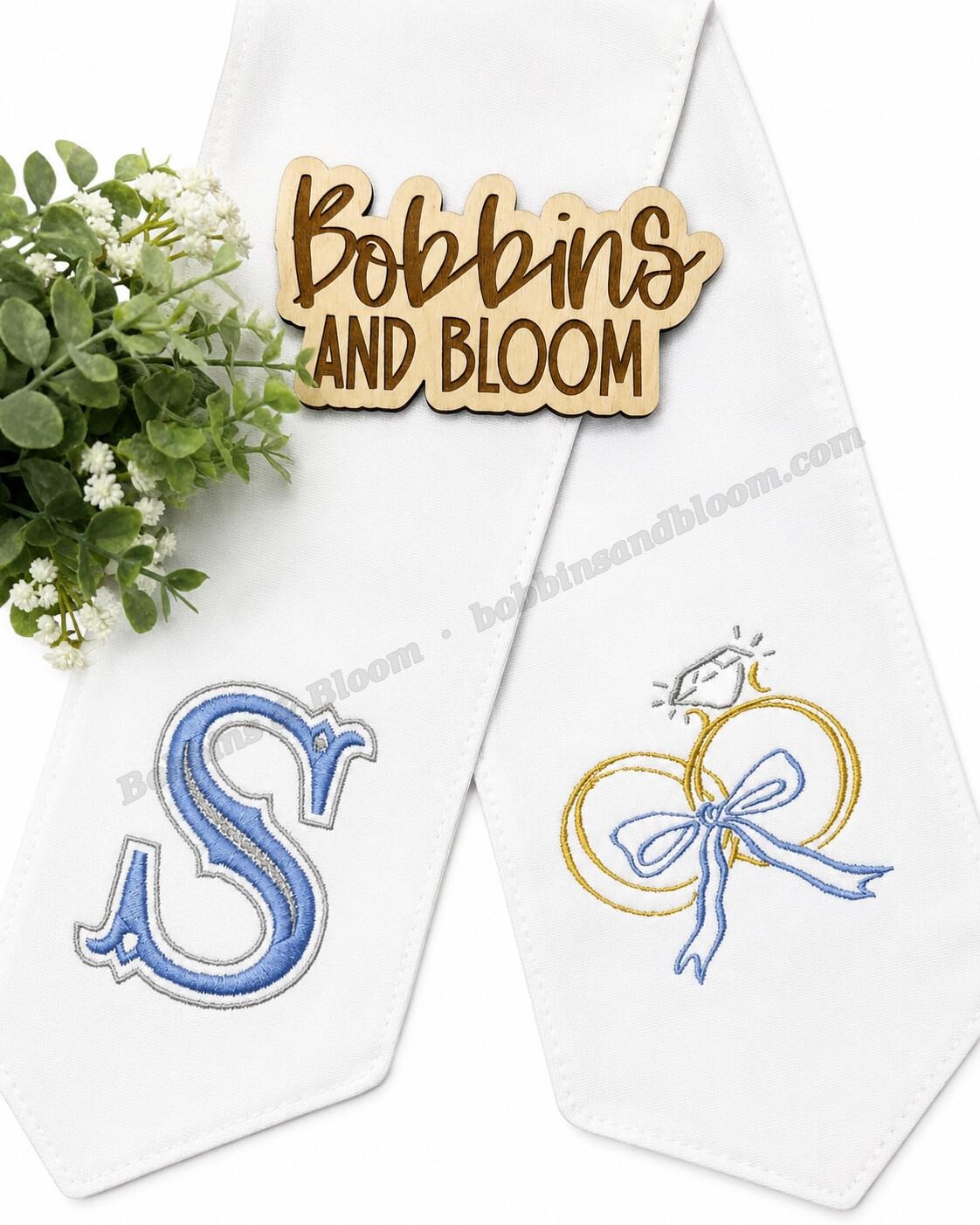 White wedding wreath sash with an embroidered monogram and interlocking wedding rings with a bow